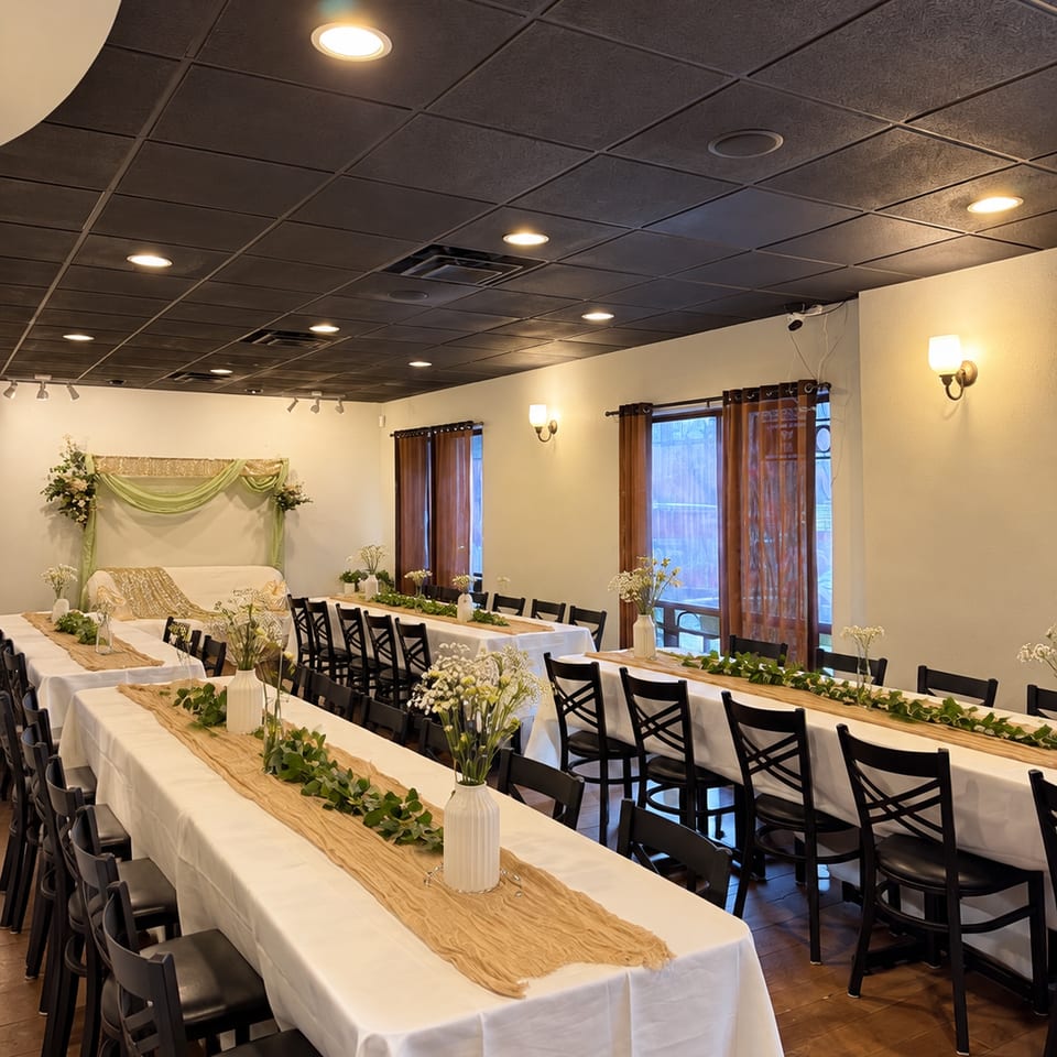 Engagement event with white tablecloths, greenery, and floral centerpieces at Kabob Cafe & Grill.